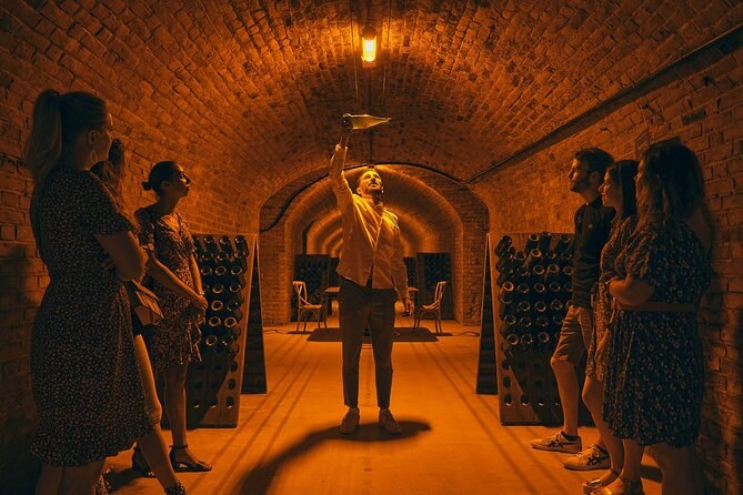 A brick-vaulted cellar gallery lit amber, riddling racks along both walls