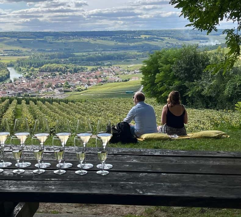 Flutes poured on a table among the vines, a town and a river valley spread out below