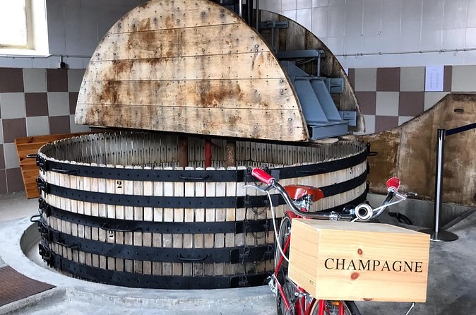 An old round wooden grape press beside a crate stamped Champagne