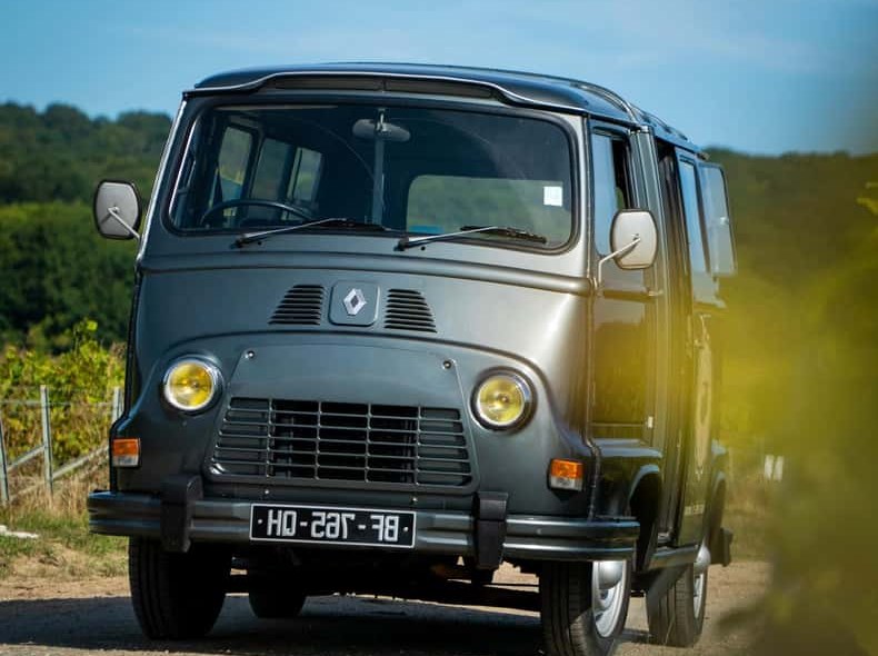 A grey vintage van parked on a track at the edge of the vines